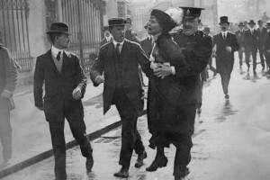 Emmeline Pankhurst sendo presa enquanto tentava apresentar uma petição ao rei no Palácio de Buckingham, em 21 de maio de 1914.